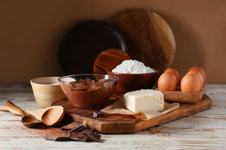 Bowl with fresh dough and ingredients for preparing chocolate brownie on tableの写真素材