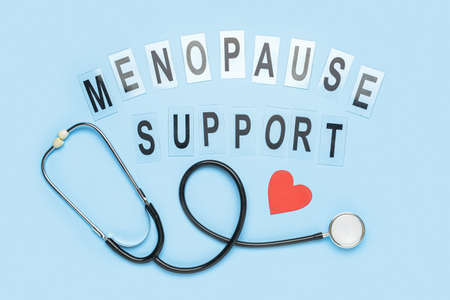 Text MENOPAUSE SUPPORT with paper heart and stethoscope on blue background