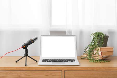Modern laptop and microphone on table in studioの写真素材