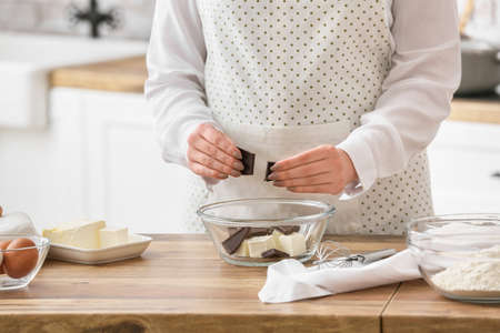 Woman preparing chocolate brownie at kitchen table, closeup