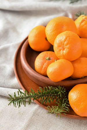 Plates with tangerines and fir branches on light fabric background, closeupの写真素材