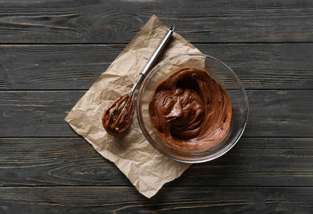Bowl with fresh dough for preparing chocolate brownie on dark wooden backgroundの写真素材