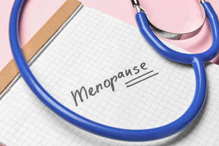 Notebook with word MENOPAUSE and stethoscope on pink background, closeupの写真素材