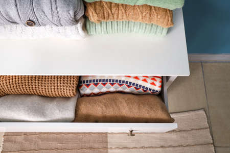 Stacks of sweaters and opened drawer with warm clothes, closeupの写真素材