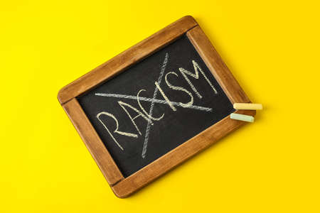 Chalkboard with crossed out word RACISM on color backgroundの写真素材