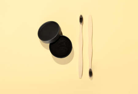 Jar with activated charcoal tooth powder and toothbrushes on yellow backgroundの写真素材