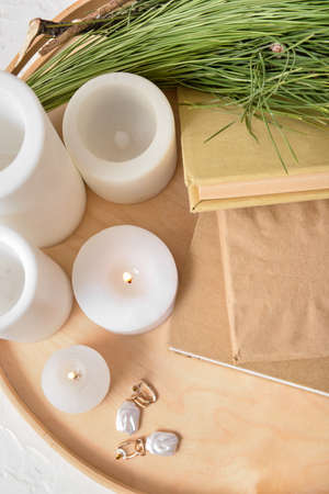 Tray with books, candles, earrings and fir branches on white backgroundの写真素材