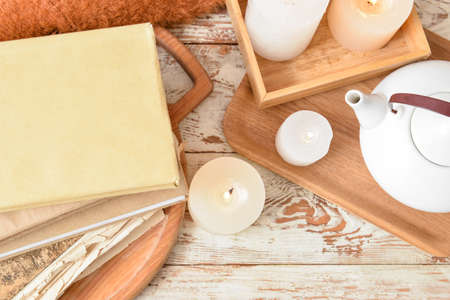 Stack of books with burning candles and teapot on light wooden backgroundの写真素材
