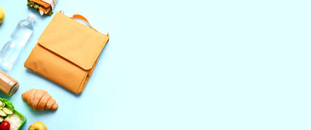 Child's bag with different food and bottle of water on light blue background with space for text