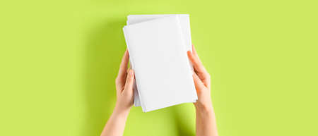 Female hands with blank books on green background