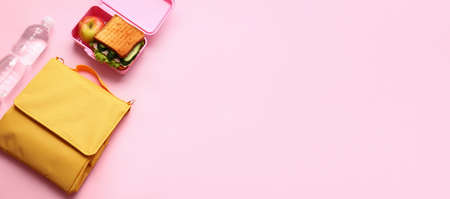 Child's bag with bottle of water and lunchbox with tasty food on pink background with space for textの写真素材