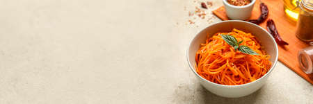 Bowl with spicy Korean carrot salad on gray background with space for textの写真素材