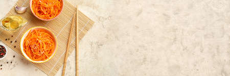 Bowls with spicy Korean carrot salad on grunge background with space for textの写真素材