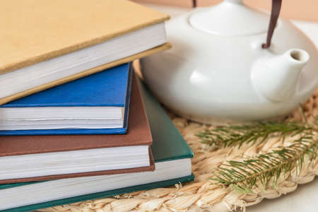 Stack of books, teapot and fir branches on wicker mat, closeupの写真素材