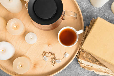 Tray with teapot, cup, candles and book on grunge backgroundの写真素材