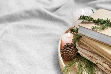 Wooden tray with books, fir tree branches and candles on plaidの写真素材