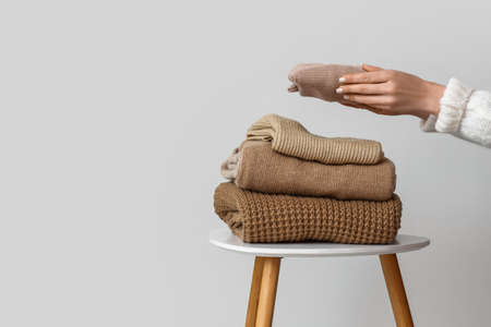 Woman beige sweater on table near putting light wallの写真素材