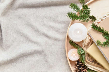 Tray with books, burning candles and fir tree branches on plaidの写真素材