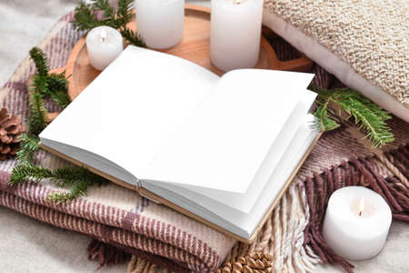 Opened book with blank pages and burning candles on plaidの写真素材