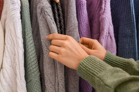 Woman near rack with warm sweaters, closeupの写真素材