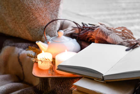 Tray with opened book, burning candles and tea pot on windowsillの写真素材