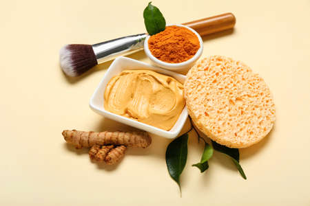 Bowl with turmeric mask, powder and makeup brush on beige backgroundの写真素材