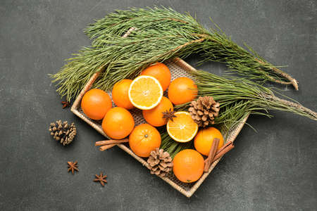 Wicker box with fresh oranges and fir branches on black backgroundの写真素材