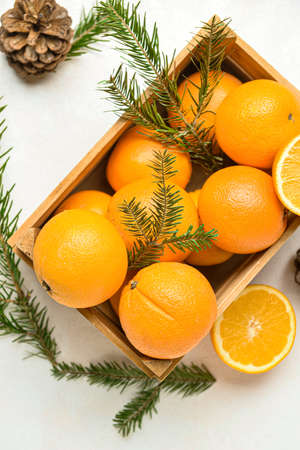 Wooden box with fresh oranges and fir branches on white backgroundの写真素材