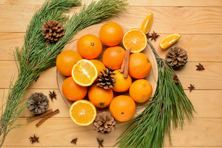 Plate with fresh oranges and fir branches on wooden backgroundの写真素材
