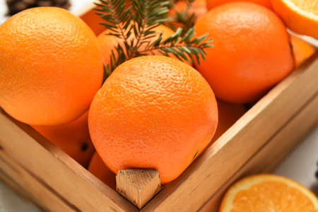 Wooden box with fresh oranges on table, closeup