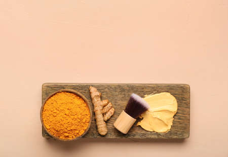 Board with turmeric mask, powder and makeup brush on beige backgroundの写真素材