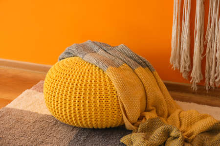 Modern pouf and plaid near color wall in room, closeupの写真素材