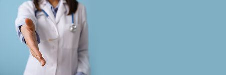 Female doctor giving hand for shake on blue background with space for textの写真素材