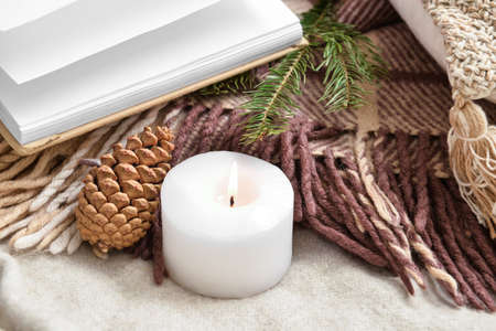 Burning candle, pine cone and fir tree branch on plaidの写真素材