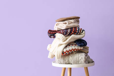 Stack of winter sweaters on table near lilac wallの写真素材