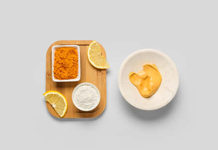Bowl with turmeric mask, different powder and lemon on gray backgroundの写真素材