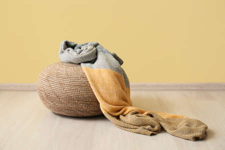 Beige pouf with plaid near yellow wallの写真素材