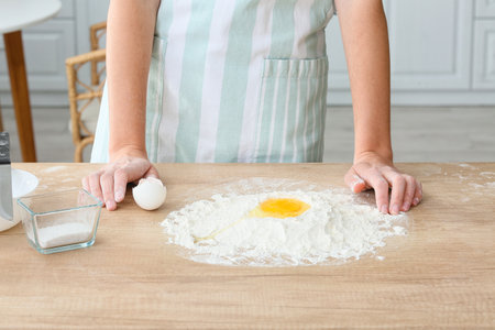 Young woman making dough on table in kitchen, closeupの写真素材