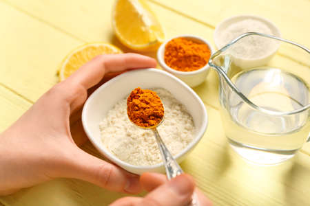 Woman making turmeric mask on color wooden background, closeupの写真素材