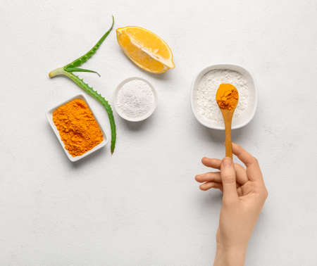 Woman making turmeric mask on light backgroundの写真素材