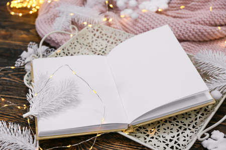 Opened book with blank pages, beautiful decor and glowing lights on wooden backgroundの写真素材