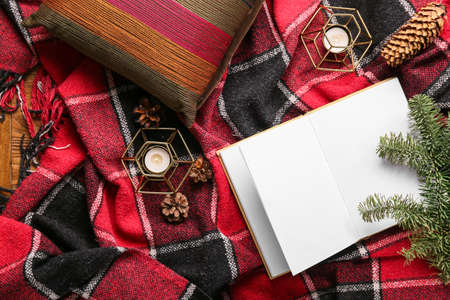 Opened book with blank pages, burning candles and winter decor on plaidの写真素材