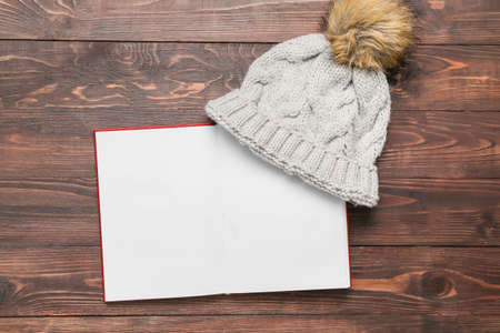 Opened book with blank pages and knitted hat on wooden backgroundの写真素材