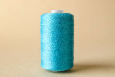 Blue sewing thread spool on light backgroundの写真素材