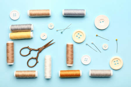 Sewing thread spools, buttons, scissors and pins on color backgroundの写真素材