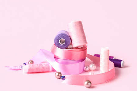 Sewing thread spools and ribbons on color backgroundの写真素材