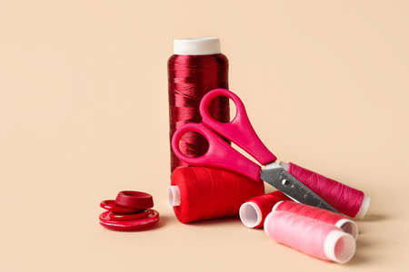 Sewing thread spools, buttons and scissors on light backgroundの写真素材