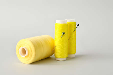 Yellow sewing thread spools with pins on light backgroundの写真素材