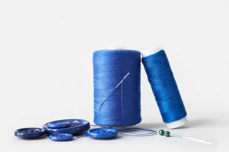 Sewing thread spools, needles, pins and buttons on white backgroundの写真素材