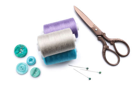 Sewing thread spools, scissors and buttons on white background